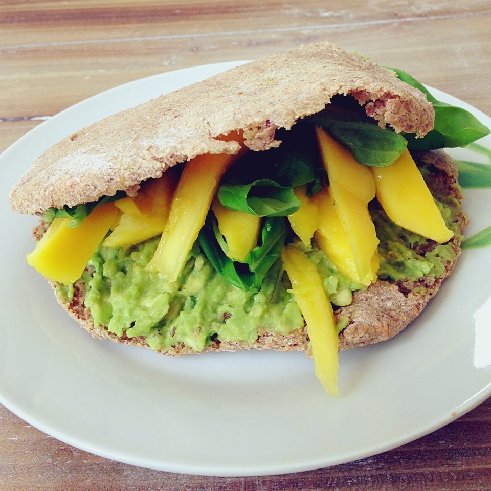 Homemade whole wheat and flax seed pita with mashed avocado, mango slices and fresh basil leaves, fresh summer lunch!